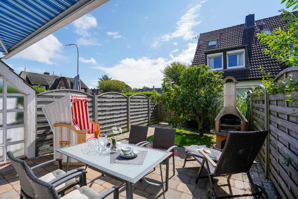 eine Terrasse mit Tisch und Stühlen und einem Zaun in der Unterkunft Süderliebe in Westerland