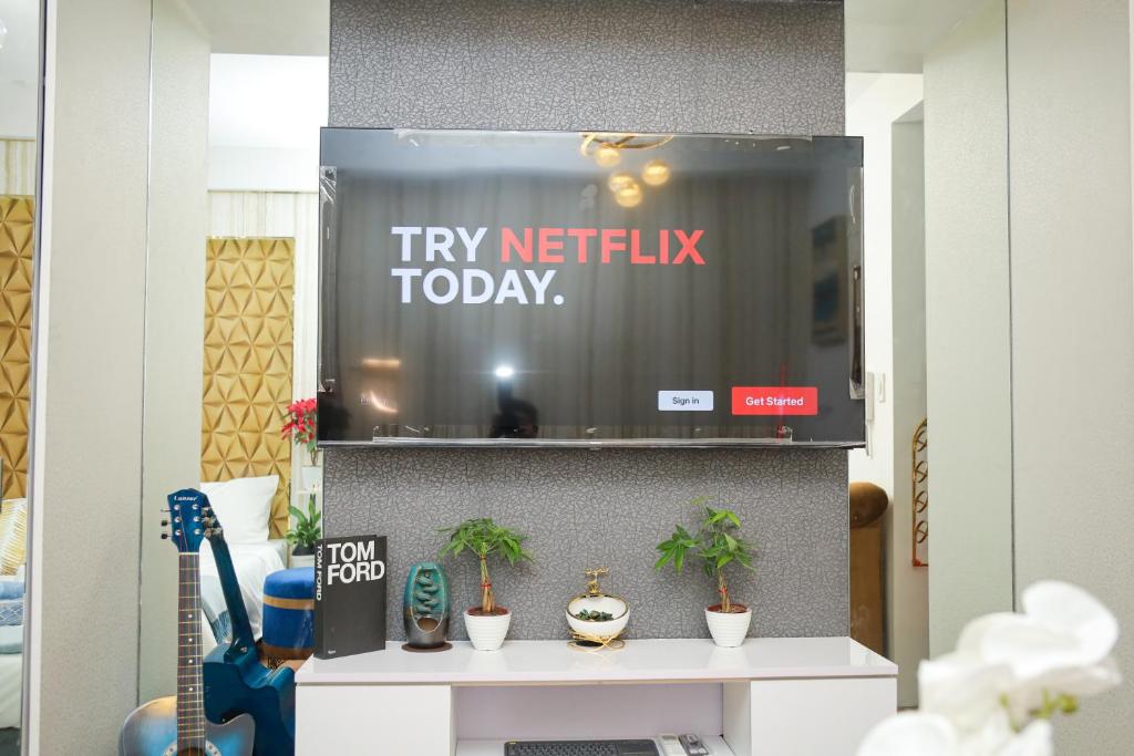 a tv netflix display in a room with potted plants at Shore2 Luxurious & Homely Suite near MOA in Manila