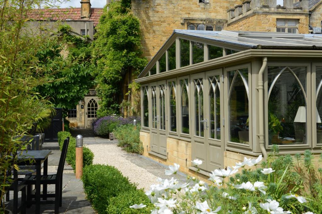 a greenhouse in a garden with white flowers at The Manor House Hotel in Moreton in Marsh