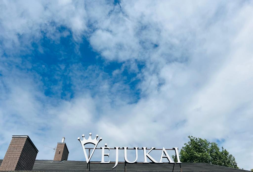 un panneau au-dessus d'un bâtiment avec un ciel bleu dans l'établissement Vėjukai, à Viduklė