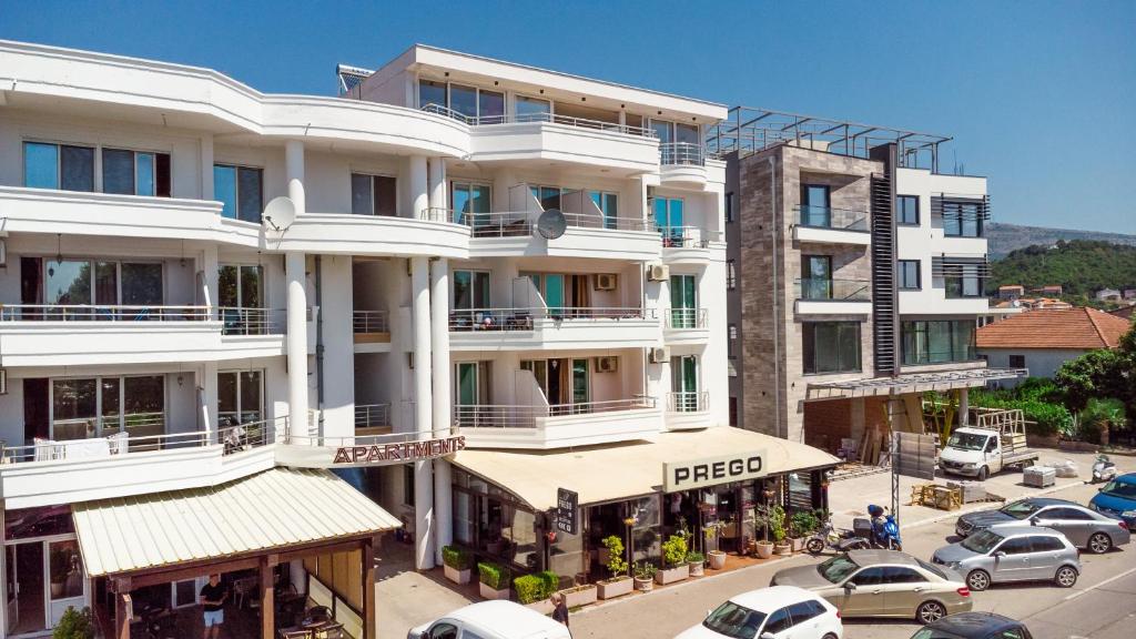 a large white building with cars parked in a parking lot at Apartment Hotel Prego in Ulcinj