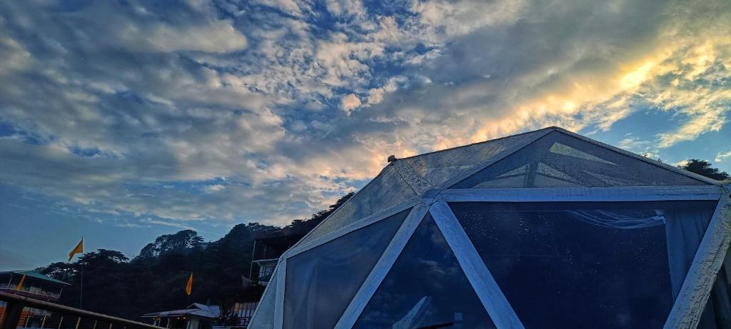 ein Gebäude mit einem Himmel im Hintergrund mit Wolken in der Unterkunft Starlit Dome Mcleodganj in Dharamshala