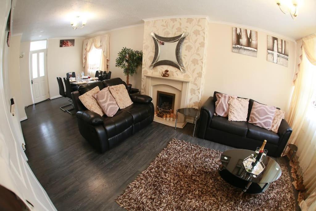 a living room with black leather furniture and a fireplace at Luxurious Bedworth Exhall, House in Exhall