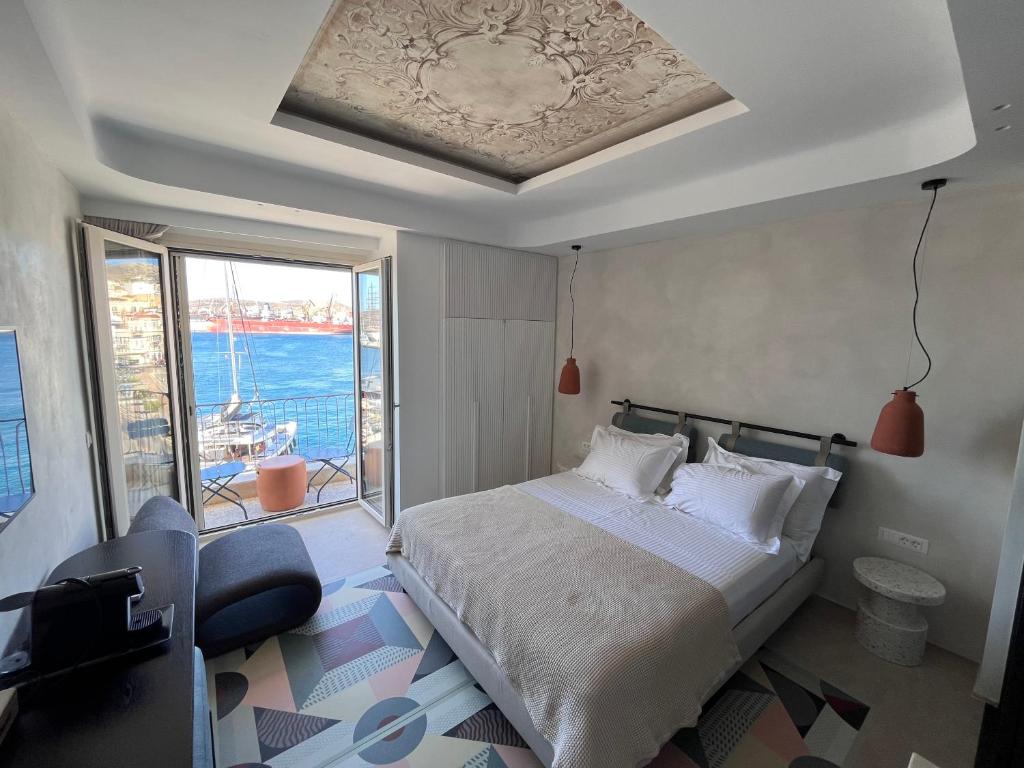 una camera con un letto e una grande finestra di Kratísti a Ermoupoli