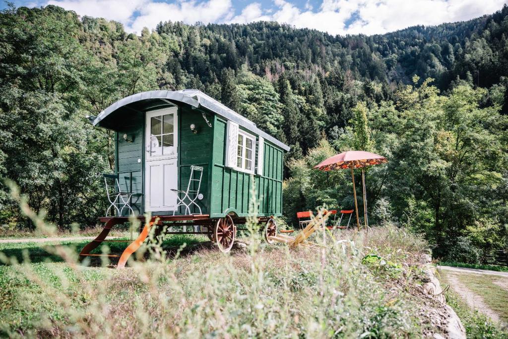 een groen huis aan de kant van een heuvel met een paraplu bij Camping Passeier Glamping Tilia in Saltusio