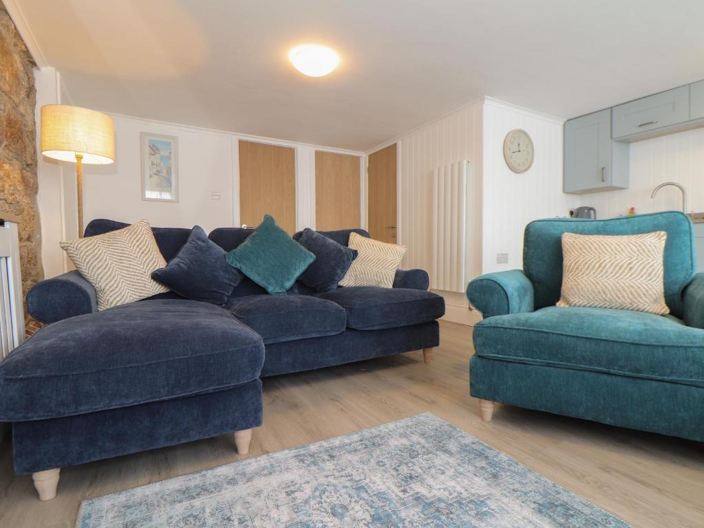 sala de estar con sofá azul y 2 sillas en Harbour Studio en Penzance