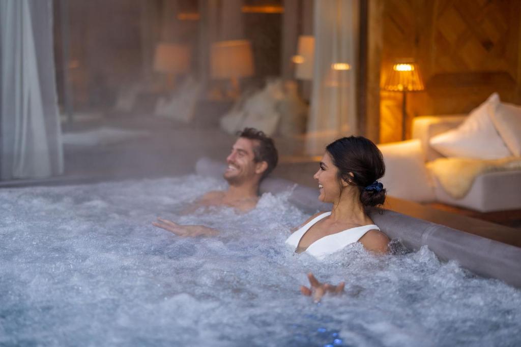 a man and a woman sitting in a hot tub at Hotel Seevilla Wolfgangsee in St. Wolfgang