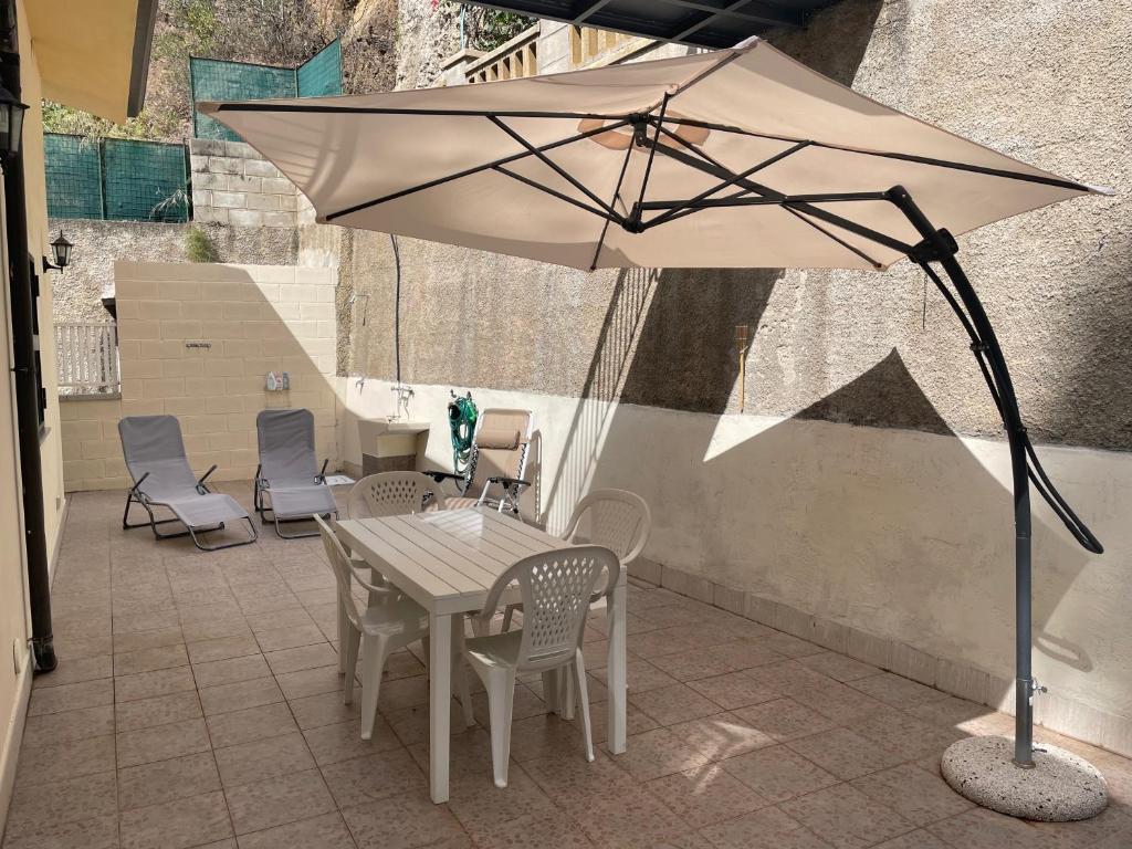 un tavolo con sedie e un ombrellone su un patio di Casa Il Sole a Piraino