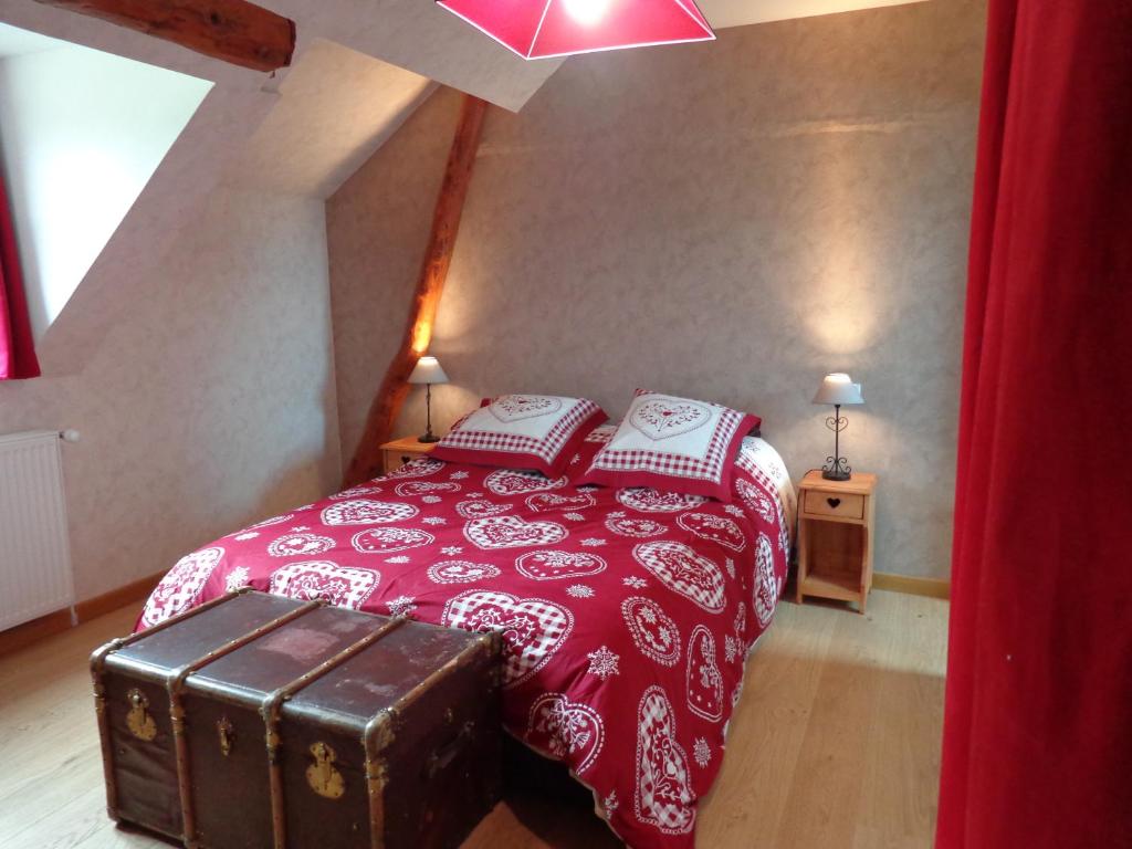 a bedroom with a bed with a red blanket and a trunk at La Boucle de l'Adour Chambres d'Hôtes & gîtes in Campan