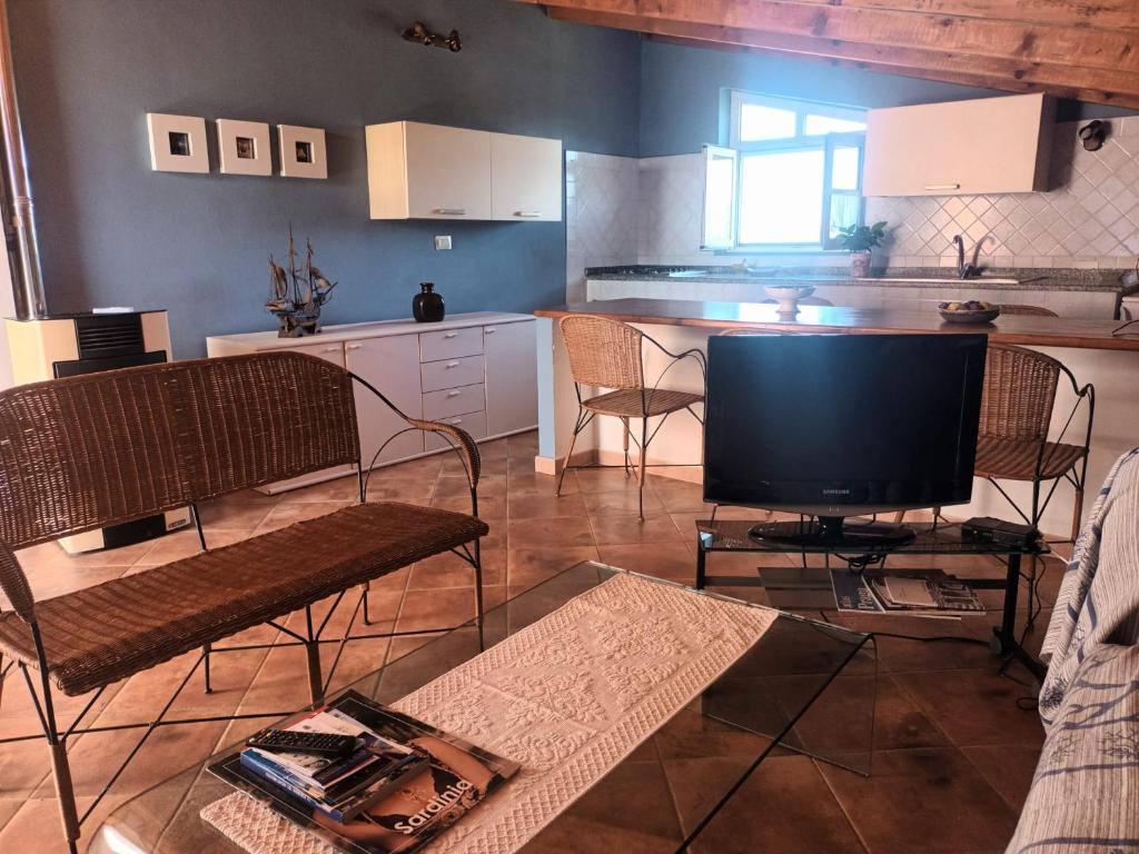 ein Wohnzimmer mit einem TV und einer Küche in der Unterkunft Il Vecchio Lentisco in Alghero