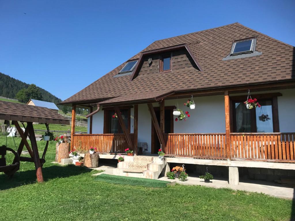 a house with a porch and a yard at Căsuța din munți in Sadova