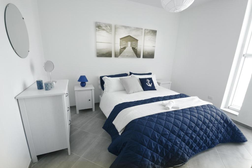 una camera con un letto e un piumone blu e bianco di Hypogeum Suites & Apartments a Otranto