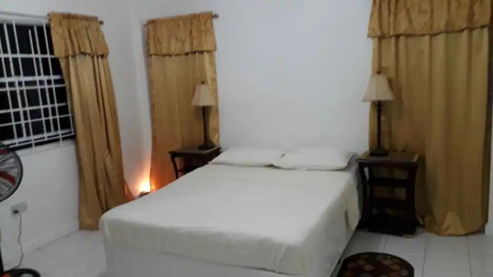a bedroom with a white bed and two night stands at Lynn's Place in Castries