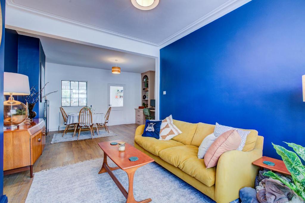a living room with a yellow couch and a blue wall at Pass the Keys Cosy house on the seafront in Southend-on-Sea
