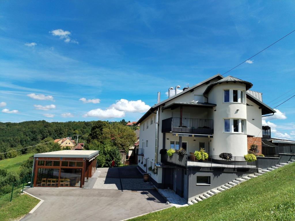 a white house with a balcony and a building at Guesthouse Frlan in Ozalj