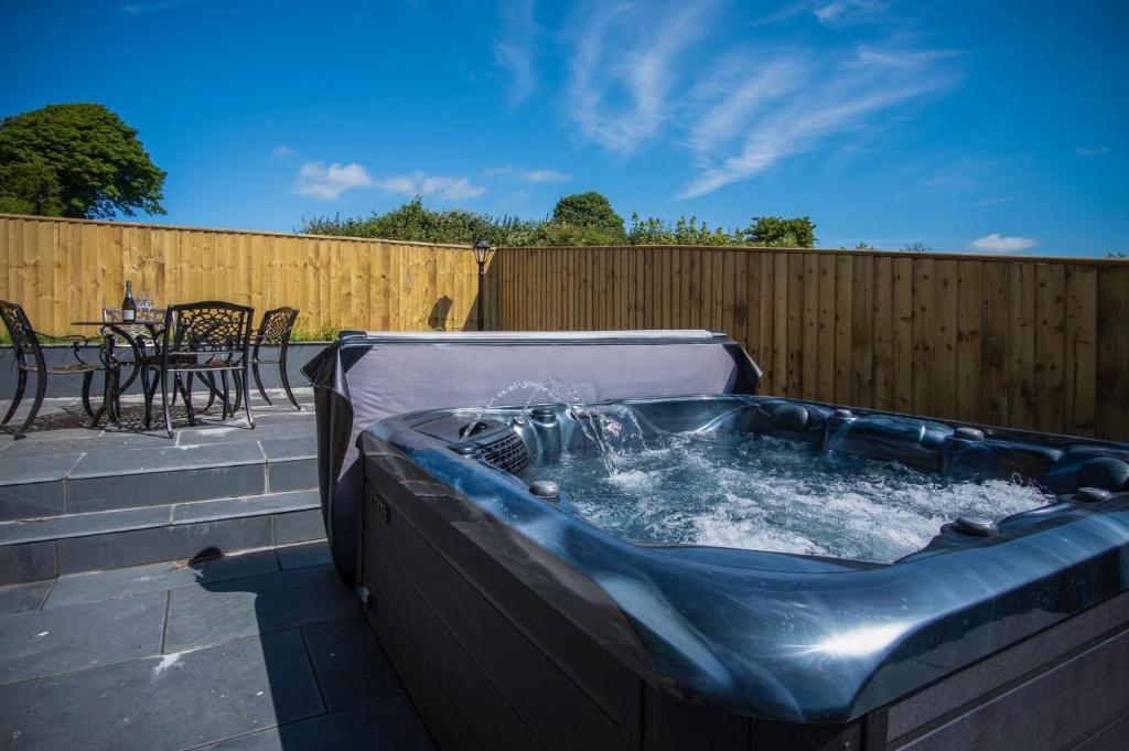 a hot tub on a patio with a table at Anchor Well - 2 Bedroom Cottage - Ludchurch in Ludchurch