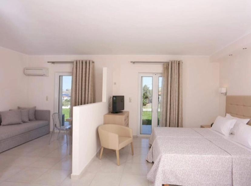 a bedroom with a bed and a couch and a tv at Ammos Suites in Platy
