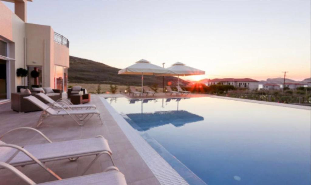 a swimming pool with chairs and umbrellas on a building at Ammos Suites in Platy