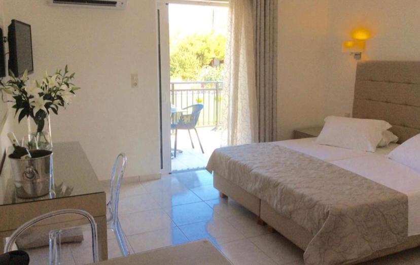 a bedroom with a bed and a table and a balcony at Ammos Suites in Platy