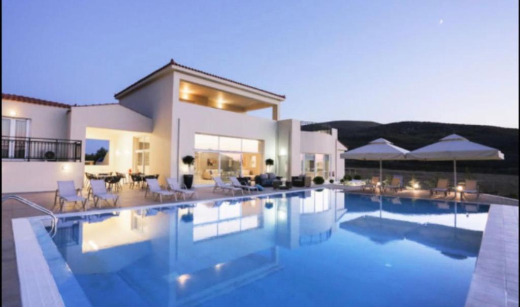 a large house with a swimming pool in front of it at Ammos Suites in Platy