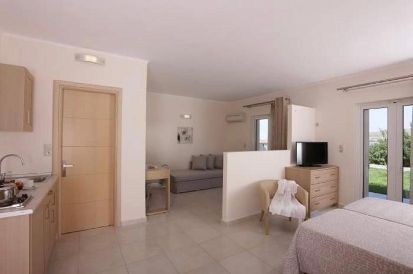 a bedroom with a bed and a kitchen with a couch at Ammos Suites in Platy