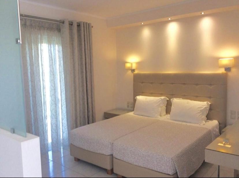 a bedroom with a large white bed with white pillows at Ammos Suites in Platy
