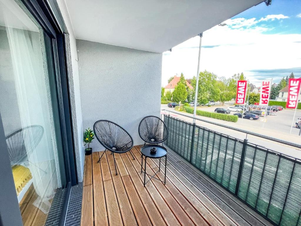 two chairs on a balcony with a view of a street at theSunset Club - STUDIO Küche - Balkon - Parken in Memmingen