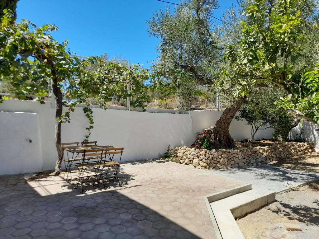 a patio with a table and a bench and trees at Olive tree cottage in Elia Laconias