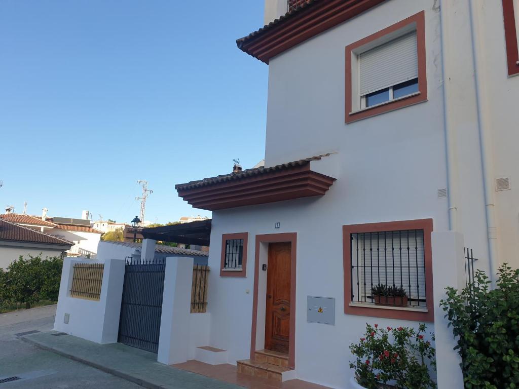 a white house with a brown door on a street at El Burré in Tolox