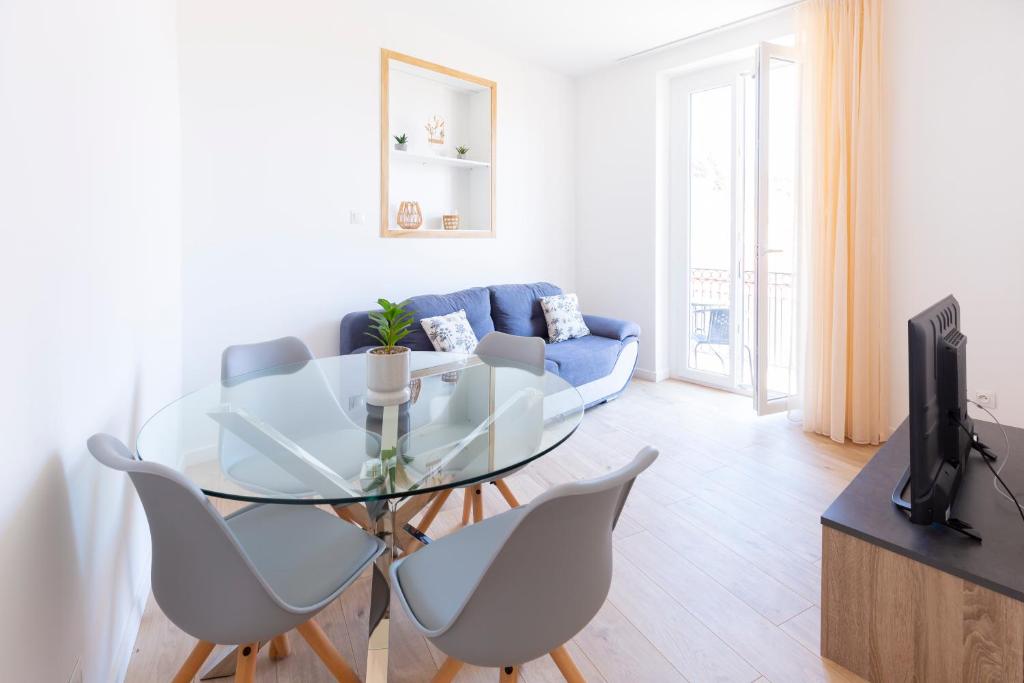 ein Wohnzimmer mit einem Glastisch und einem blauen Sofa in der Unterkunft MARNE II - 3 PIÈCES - PARKING - Carré d'or Menton in Menton
