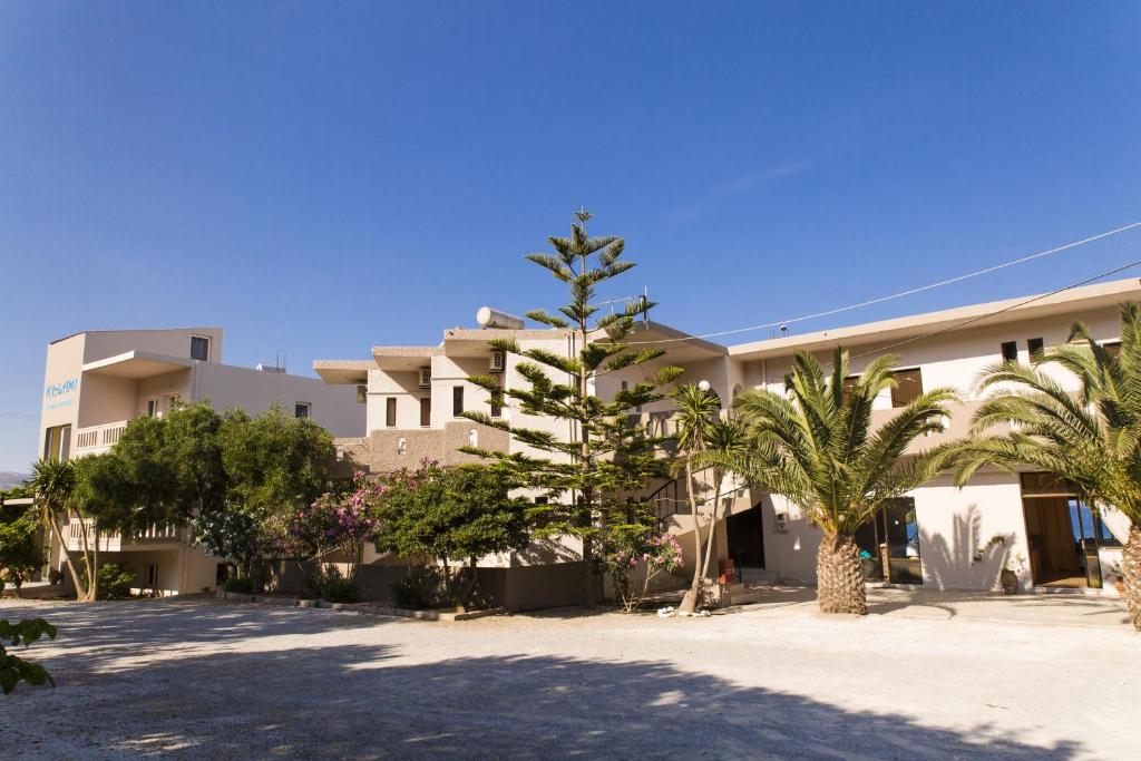 a large white building with palm trees in front of it at Kalami Rooms in Falasarna
