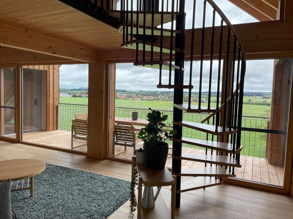a spiral staircase in a wooden house with a view of the countryside at Bummler Hof Allgäu in Legau