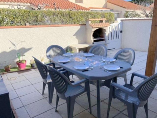 una mesa azul y sillas en un patio en Agréable Maison Résidence au calme - terrasse- parking privé - 6ANI84 en Le Barcarès