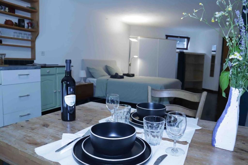 una mesa con platos y copas y una botella de vino en Casa al Bosco, en Gordevio