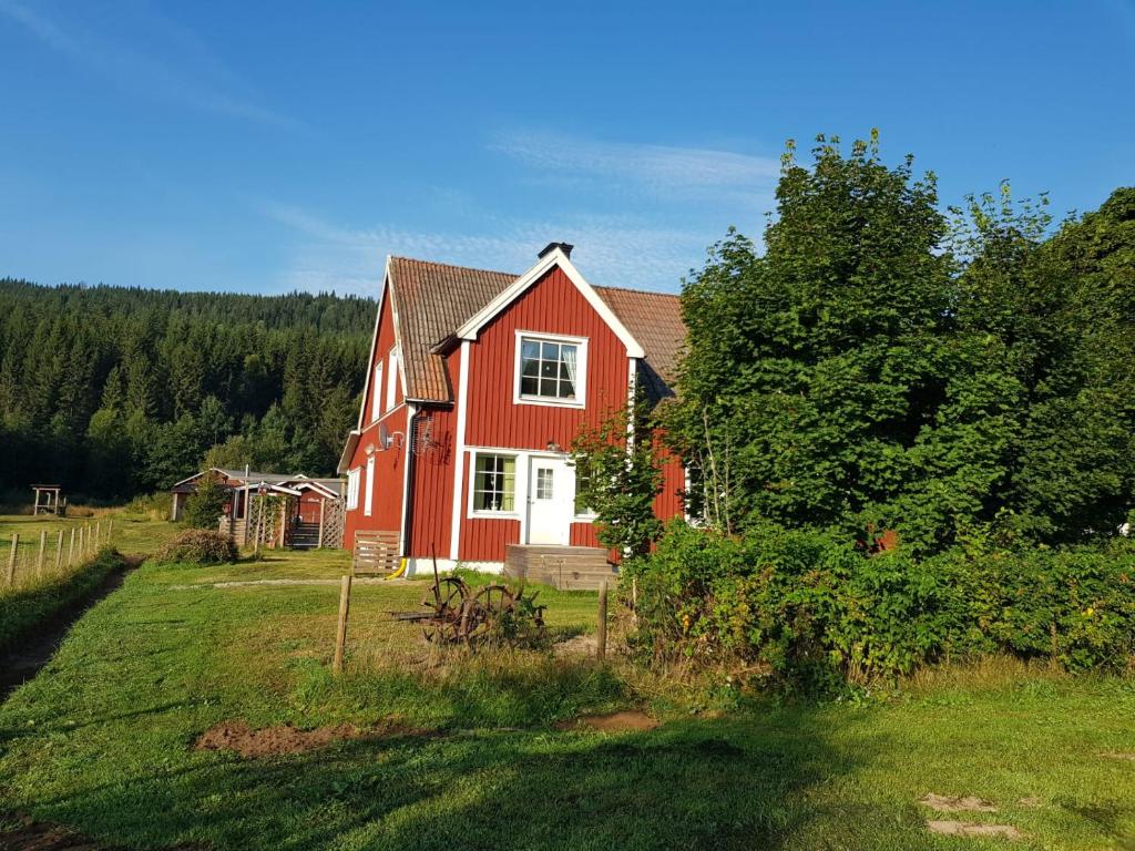 czerwony dom na polu z drzewem w obiekcie Ferienhaus Segenäs Schweden w mieście Stöllet