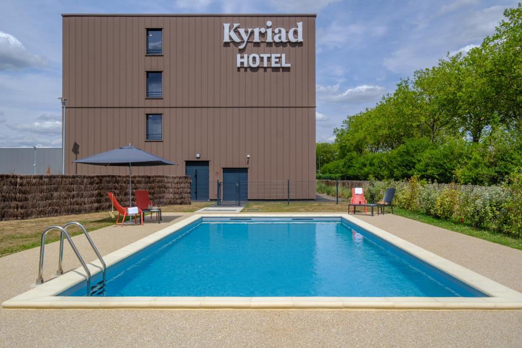 a swimming pool in front of a hotel at Kyriad Tours Sud - Ballan Mire in Ballan-Miré