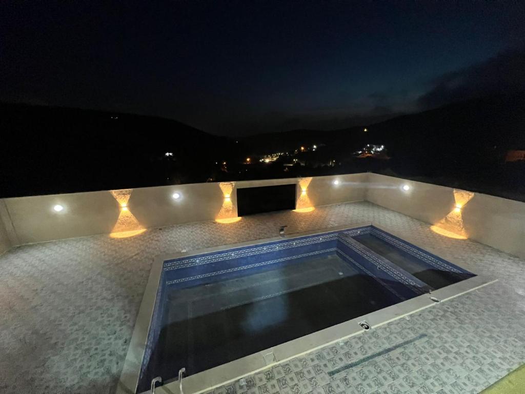a swimming pool on top of a building at night at Gernatah Farm مزرعة غرناطه in Ajloun