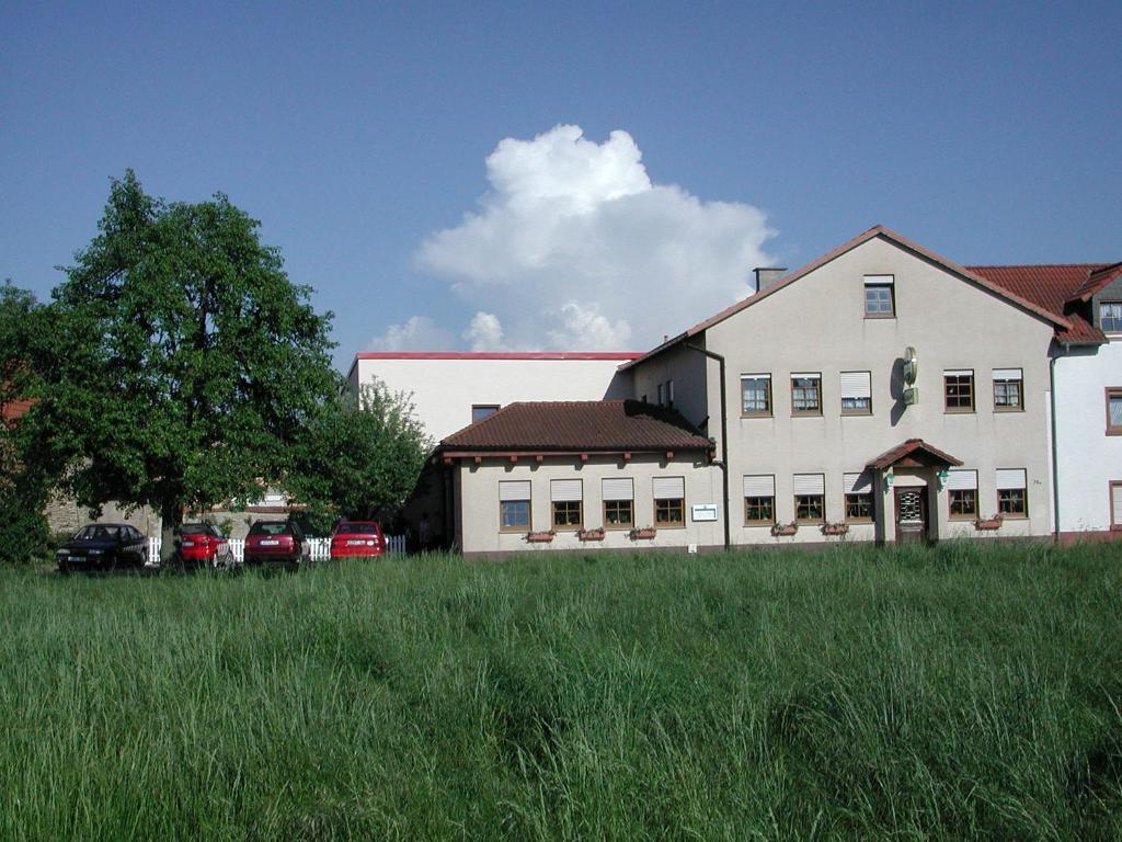 a large white building with a grass field in front of it at Gästehaus Stephanie in Ilbesheim