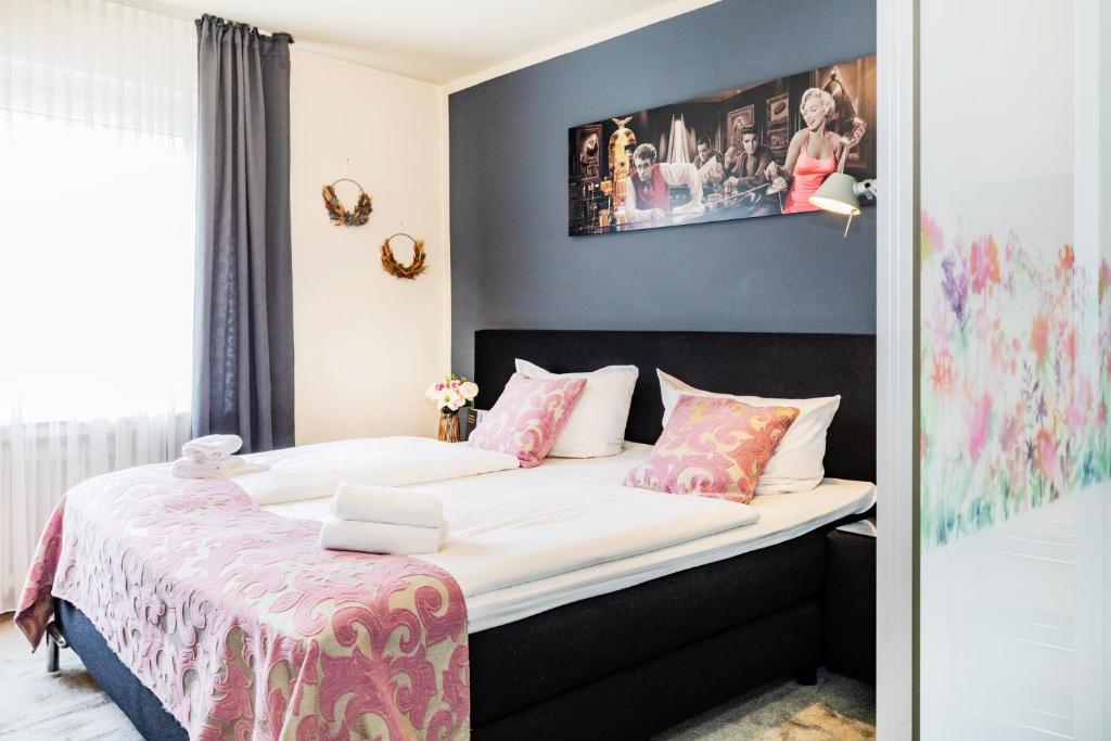 a bedroom with a bed with white sheets and pink pillows at Hotel Fürst Garden in Dortmund