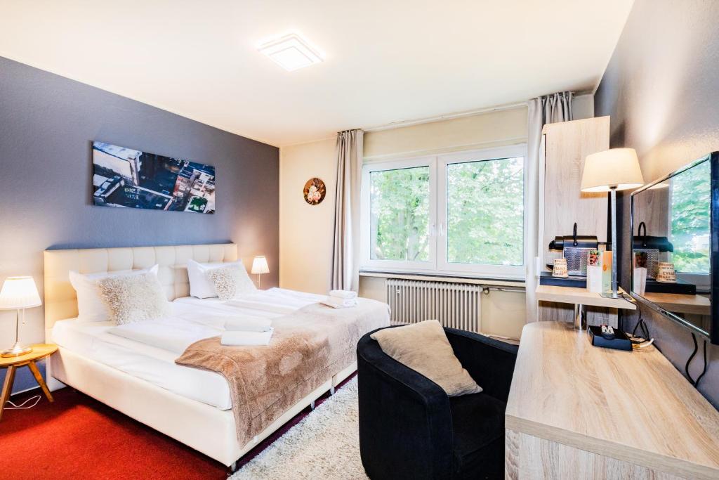 - une chambre avec un lit blanc et un canapé dans l'établissement Hotel Fürst Garden, à Dortmund