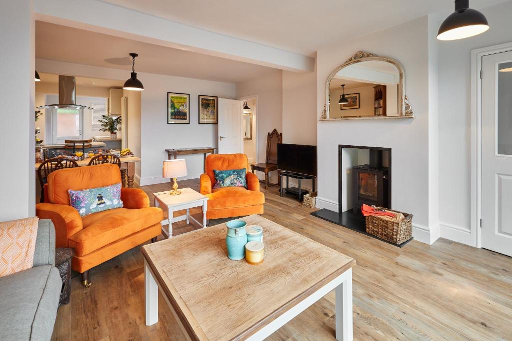 a living room with orange furniture and a fireplace at Host & Stay - The View at Orchard View in Hognaston