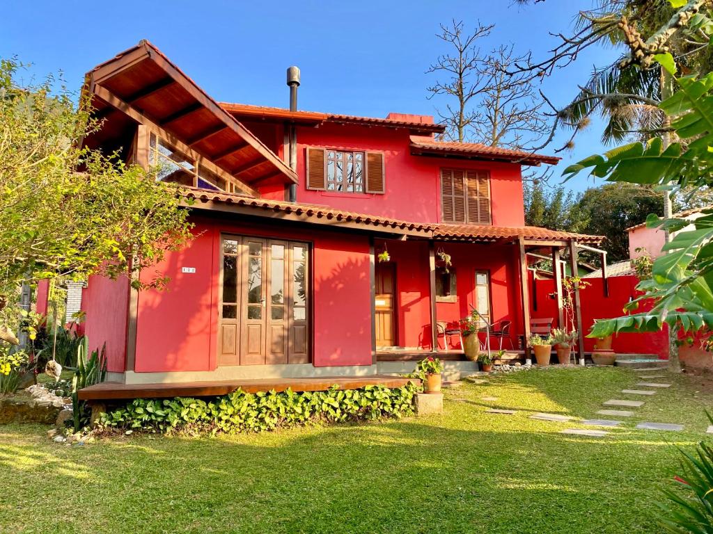 uma casa vermelha com um jardim verde em casa Encantadora em Florianópolis