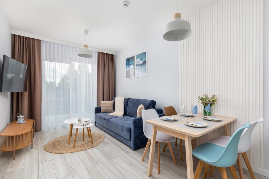 a living room with a blue couch and a table at Beach Apartments Perłowa Przystań Sztormowa by Noclegi Renters in Sianozety