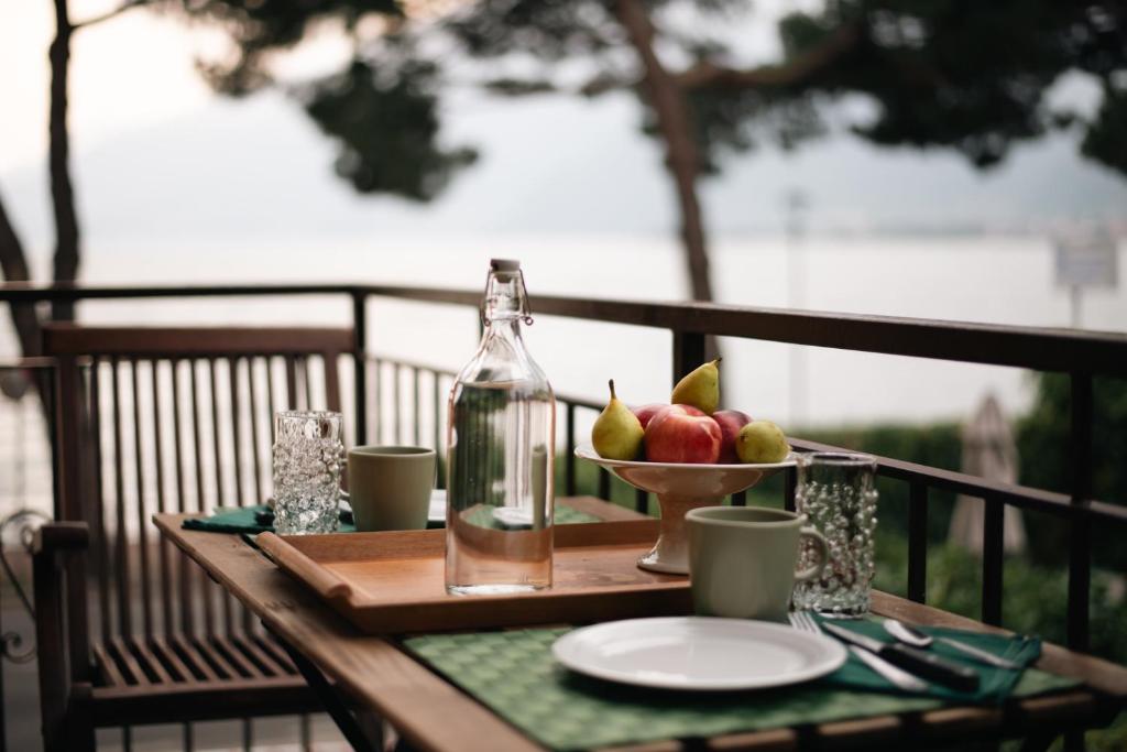 a table with a bowl of fruit and a bottle at Appartamento Lungolago in Domaso