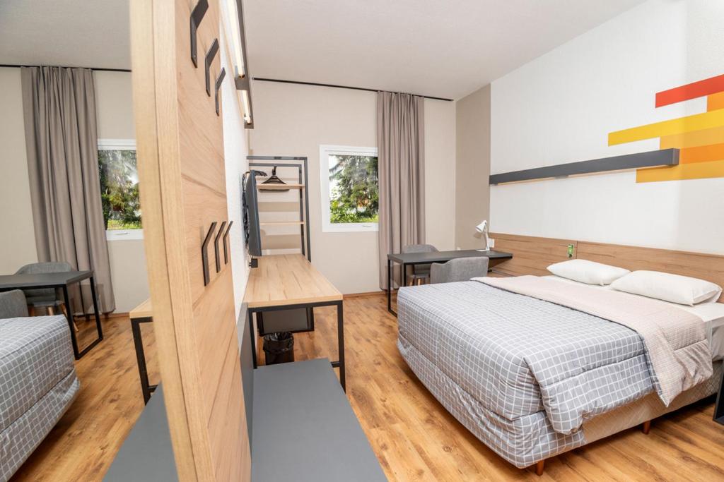 ein Hotelzimmer mit einem Bett, einem Schreibtisch und einem 6-dx-dx-Bett in der Unterkunft Hotel 10 Itajai/Navegantes in Itajaí