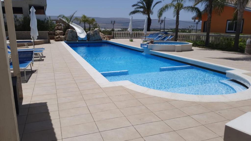 a swimming pool with a slide in a resort at La Dimora del Frappato di Tenute Senia in Chiaramonte Gulfi