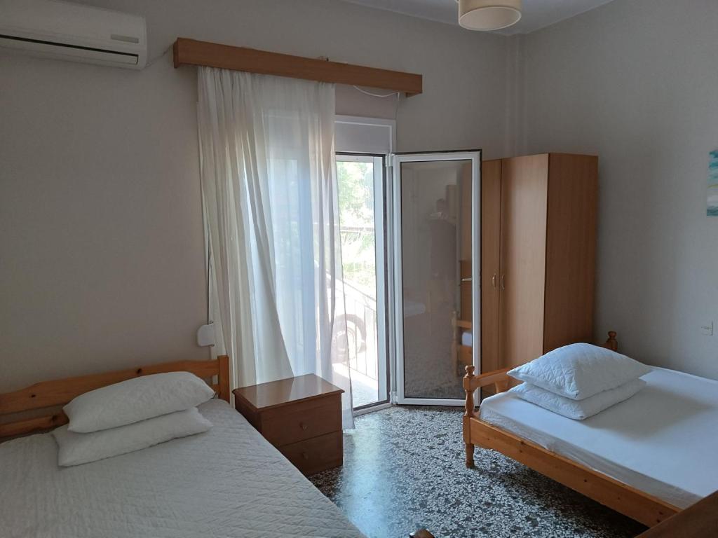a bedroom with two beds and a large window at Niki Seaside Apartments in Platamonas