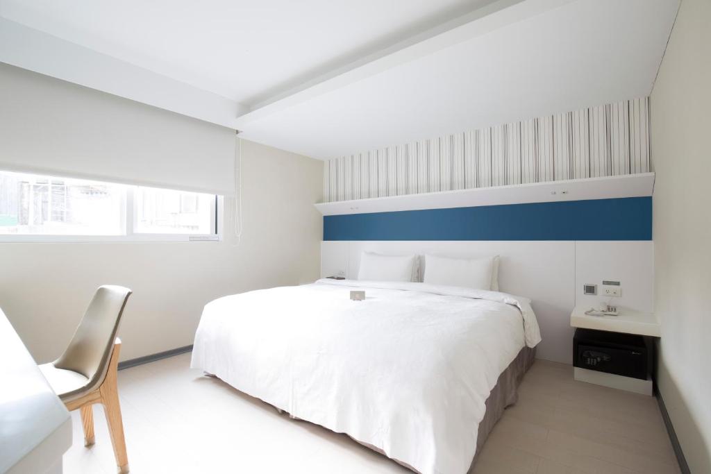 a bedroom with a white bed and a blue stripe on the wall at Dandy Hotel - Tianmu Branch in Taipei