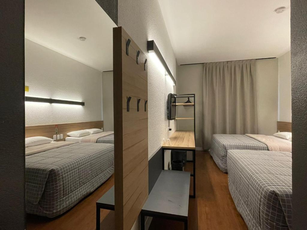 a hotel room with two beds and a television at Hotel 10 Curitiba in Curitiba