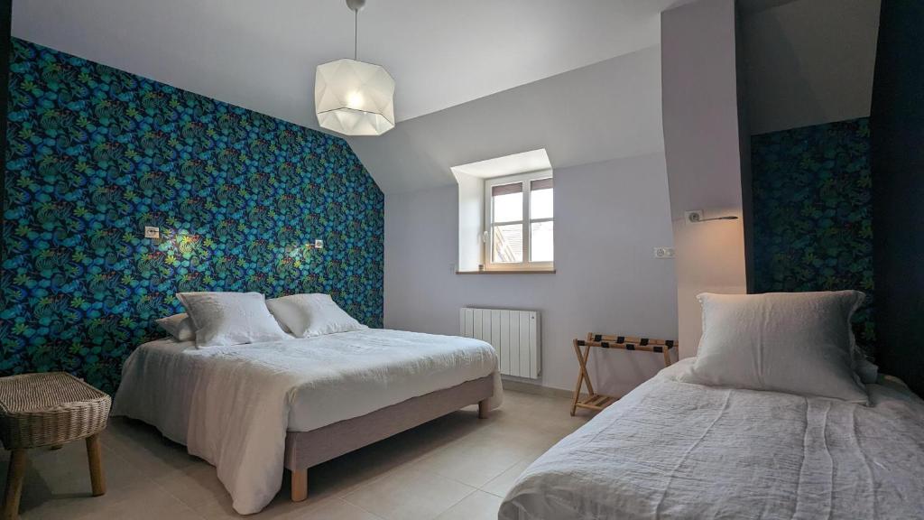 - une chambre avec 2 lits et un mur bleu dans l'établissement L'orcheran, à Vielverge